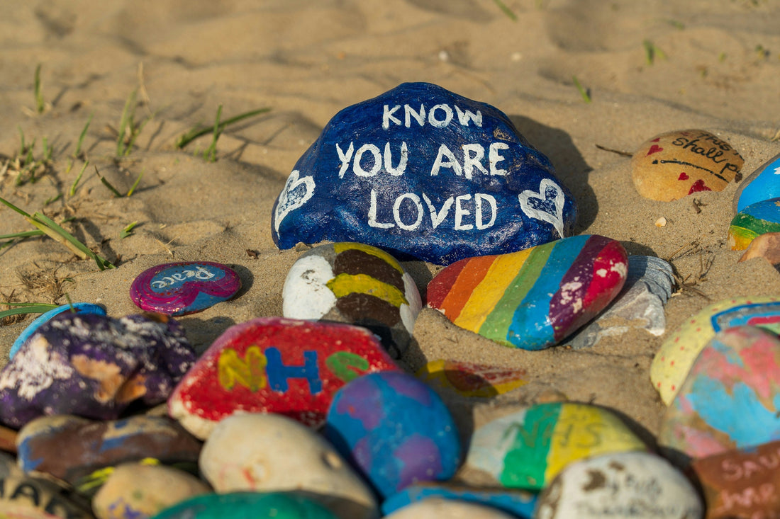 Painted rocks on sand with the message Know You Are Loved — a reminder of the power of thoughtful gestures