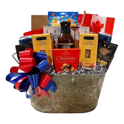 Canadian Kickback gift basket featuring gourmet snacks like water crackers, chocolate caramel bites, BBQ sauce, popcorn, cookies, and Canadian-themed items, adorned with red and blue ribbon.