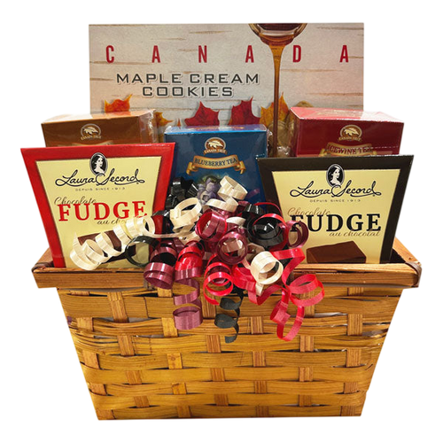 A woven gift basket featuring Canadian Made Tea and Cookies, including maple cream cookies, assorted teas, and rich fudges, adorned with festive curled ribbons for a thoughtful Canadian delivery gift.